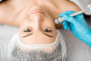 Young woman during the facial treatment procedure in the cosmetology office